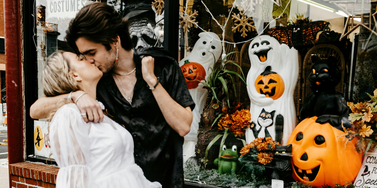 A couple kissing in front of a Halloween-themed display case