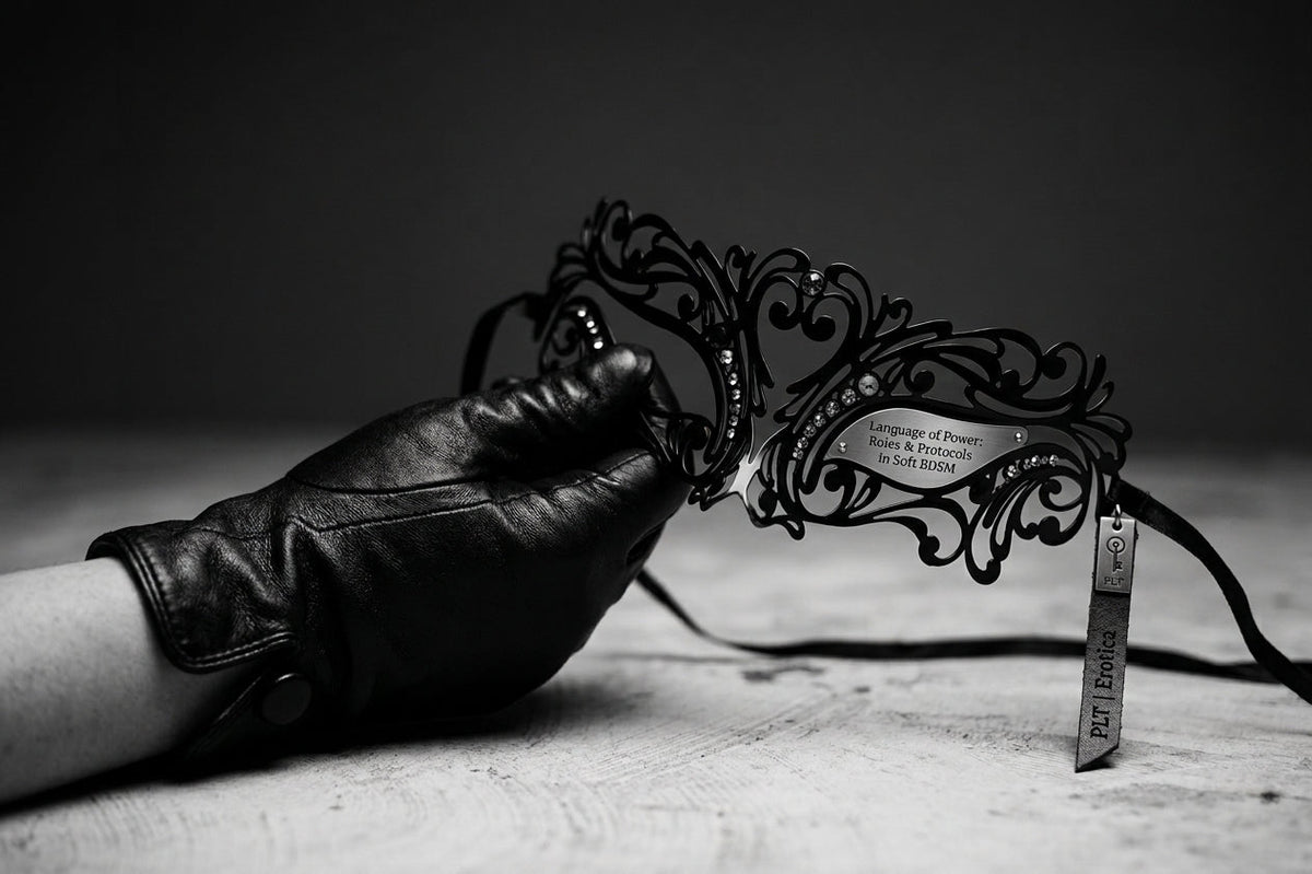 A close-up shot of a gloved hand holding an ornate black lace masquerade mask, symbolizing soft BDSM roles and protocols.