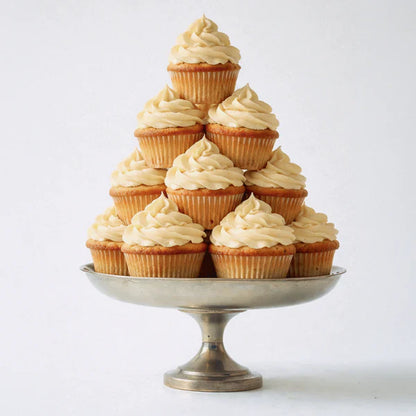 Pyramid of cupcakes with vanilla frosting on a silver cake stand against a white background
