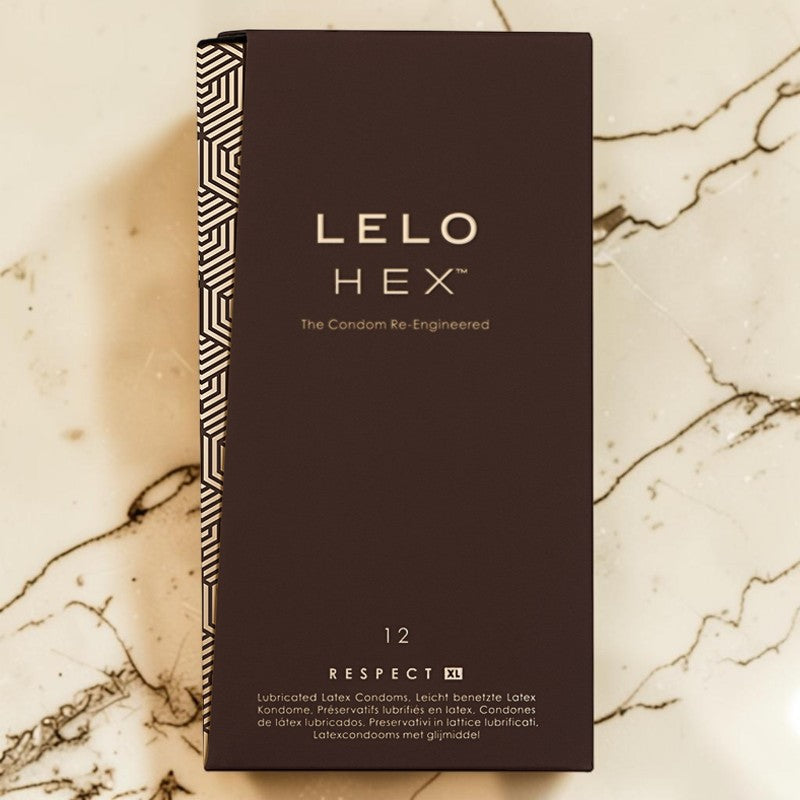 LELO HEX 12 pack of condoms in a dark brown rectangular box with a patterned spine, placed on a beige marble surface.
