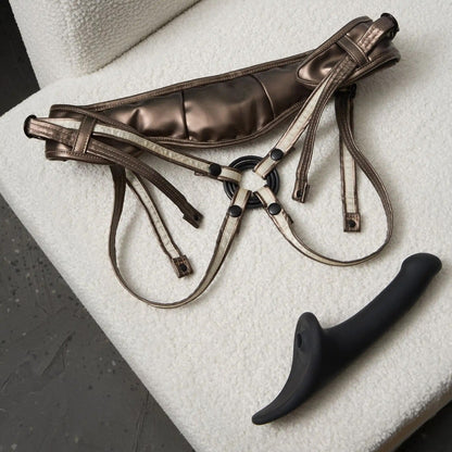 Brown leather harness with black附件 on a textured surface