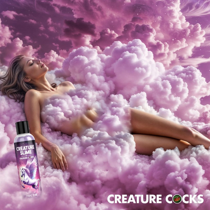 Woman lying on pink clouds with a bottle of 'Creature Cocks Creature Slime - Purple H2O Lube 8oz' in front, against a pink sky.